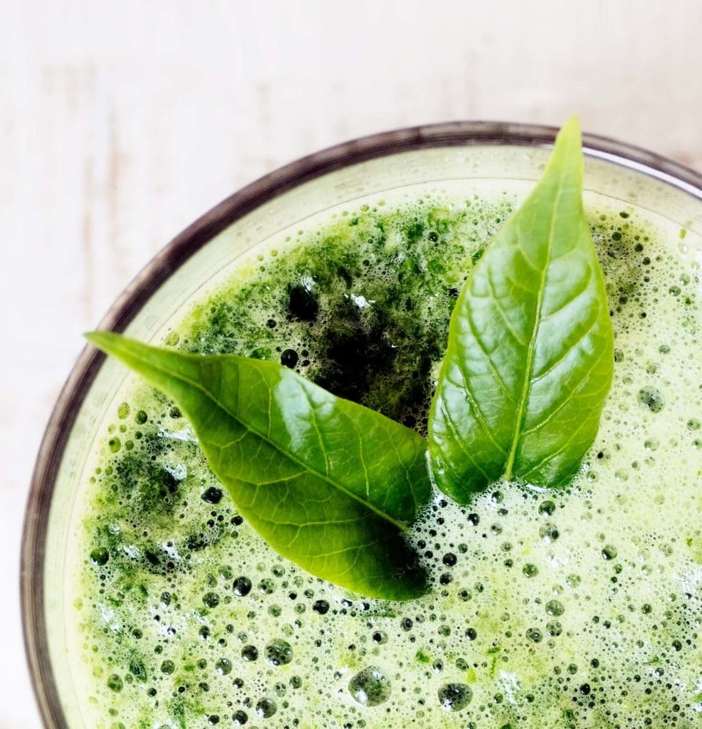 green herbal detox drink made of spinach on white wood